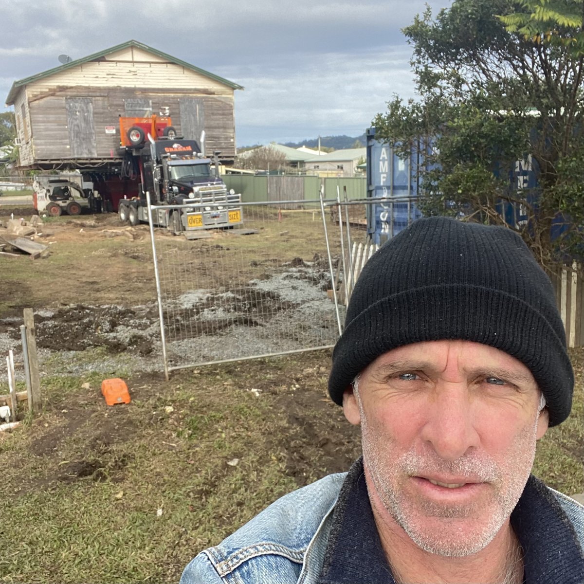 Al standing in front of a house being moved on a truck